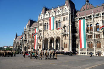 soldiers marching in front of the Parliament, that is decorate dwith the national flag