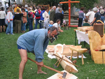 a middle-aged bearded man carving wood with an ax