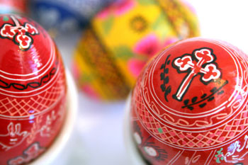 2 red and a yellow easter egg with folk motifs painted on them