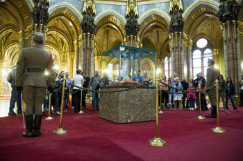 2 soldiers standing next to the Holy crown in a glass cabinet, visitors viewing the crown