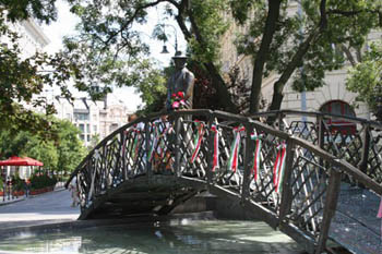 the life-size bronze statue of Imr eNagy standing on a small wood bridge