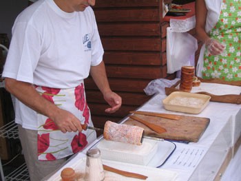 a man in white t-shirt and apron coating the pastry in sugar