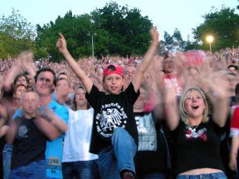 a kid in black t-shirt and red baseball cap among a crowd on a concert