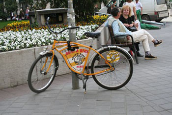 a yellow rental bike chained to a lamp post