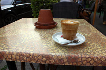 a flat white in a glass on a terra cotta table at Coytote cafe's terrace
