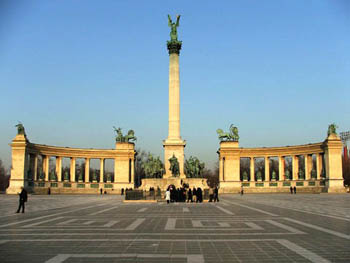 a large column with a winged angel sttaue on its top, half-circle colonnades on both its sides