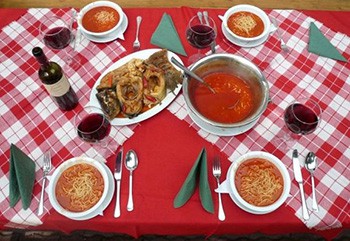 fish soup in 4 white bowls and a stainless steel bowl on a checkered table - hungarian christmas recipes