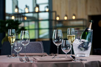 a champagne in a cooler, a couple of champagne and wine glasses on a restaurant table