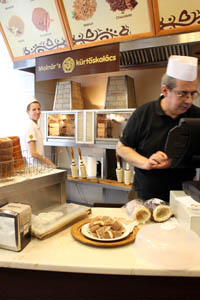 the owner, a middle-aged man wearing glasses and in white chef hat behind the counter