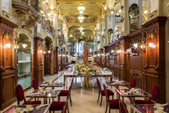 the richly decorated interior of the cafe: lots of gilded lamps, marble floor, mirrors tables in two rows