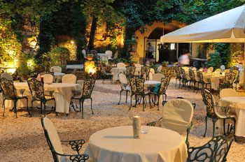 small round tables with 4 chairs in the garden of Pavillon de Paris at night