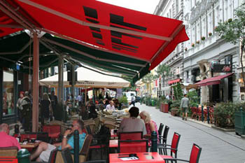 people eating on a terrace of a restaurant under a red tent