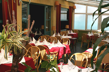 the terrace of Remiz cafe with round red-clothed tables and some potted plants