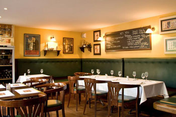 interior of Stelazsi with white clothed tables and black board with the menu on the yellow wall