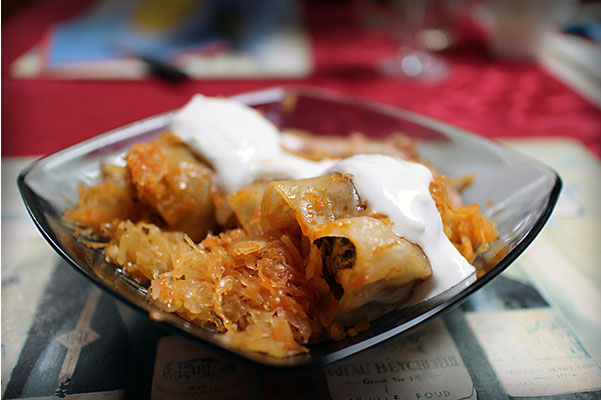 stuffed cabbage with sour cream in a square smoked glass bowl