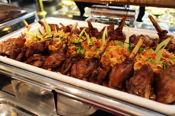 roasted goose legs arranged nicely on a stainless steel serving dish