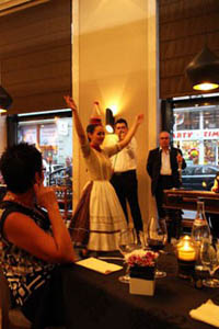 a young woman in folk costume doing a bottle dance in a restaurant