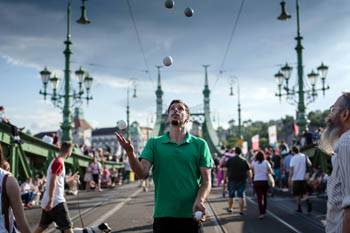 a young man in green T-shirt juggling balls on the bridge