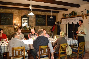 7 people sitting at the dinner table in a cellar and lisetning to Tomi Hernyák