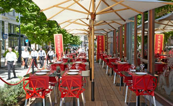 the terrace with red chairs and large beige sun umbrellas