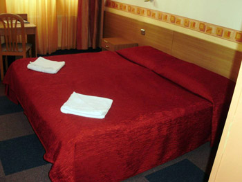 a twin bed covered with a red bedcover
