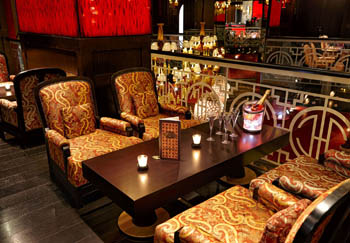 a dark brown wood table with 4 armchairs with gold upholstery