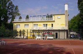 the facade of Hotel Margitsziget with a clay tennis court in front of the building