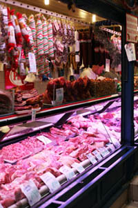 a meat counter with sausages and salamis hanging 