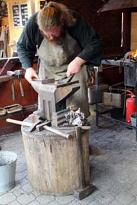 a bearded smith working in a smithy on Vörösmarty sqr.