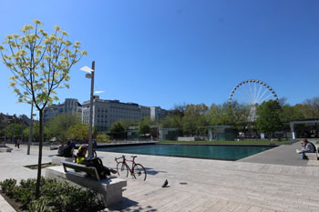 , the Eye Ferris wheel and some people sitting on benches around the lake in Erzsenet Square park