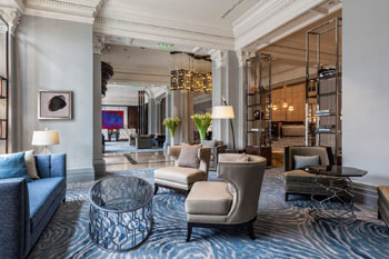 modern lobby of the Ritz Carlton Bp with blue-grey carpet, blue sofa, beige armchairs