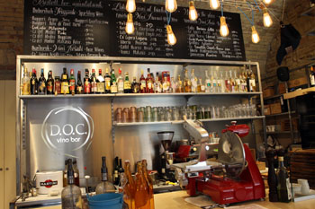 the bar area inside DOC with a red ham slicer and bottles of wine and spirits on the shelves