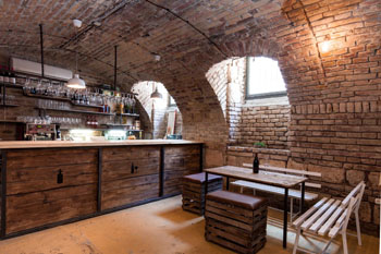 the raw brick covered vaulted interior with a woo table with benches and footstool around it