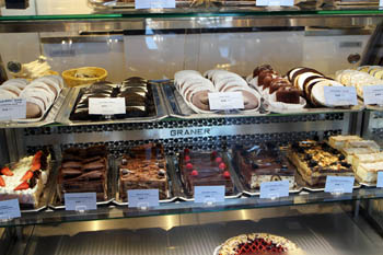a cake counter full of pastries, cakes and biscuits
