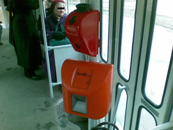 a red punch machine and an orange ticket validation machine under it on a bus