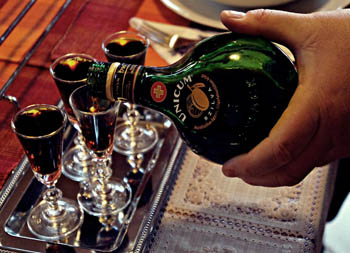 pouring the dark liqueur into shot glasses from the green glass