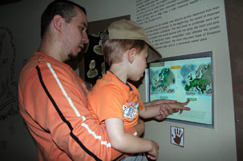 my husband holding our 4 yr boy up to the touch screen on the Ice Age exhibit