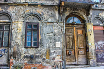 a sahbby vaulted wooden door in a rundown building