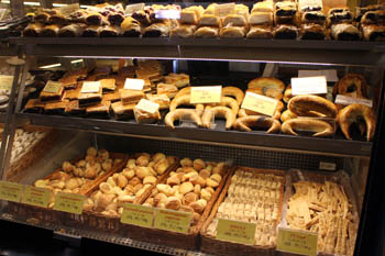 assorted bakery goods (scones, bun, bread roll, strudels) in a glass counter
