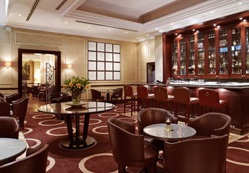 small round tables with 4 dark leather chairs around them, chocolate brown carpet with geometric design