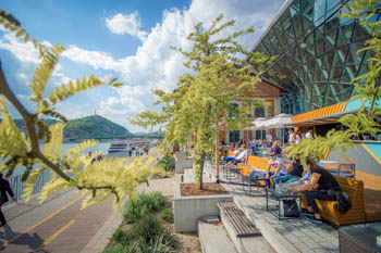 Bálna terrace: people sitting on the terrace of Bálna in Pest, overlooking the Danube on a sunny summer day