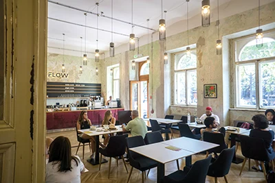 around 8-10 people having coffee and cakes sitting at square table sinside Flow Specialty Coffee & Bistro