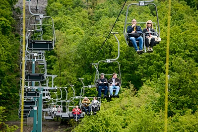 photo of the chairlift traveling up to Janos Hill in Budapest in spring, people are seating in 4 of the chairs hanging from the steel cable