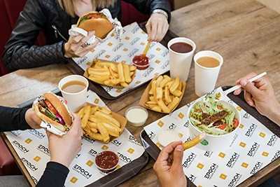 2 people having burger with fries, a 3rd vegan Caesar salad in Epoch Burger