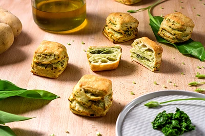 6 pieces of pogacsa flavoured with ramsons placed on a wooden table: round/square shaped Hungarian savoury pastry