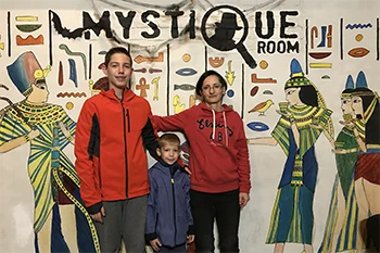 a photo me and my two sons in Mystique Room, we are standing in front of a wall depicting ancient Egyptian scenes