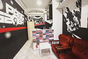 photo of the reception hall of Paniq Room in Budapest. There is  abig, comfy-looking rust colored sofa to the right. Walls are painted in balck and white.