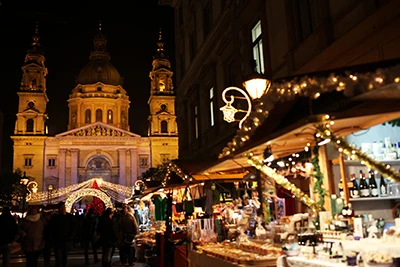 wooden booths with Xmas lighting and decorations in front of Budapest's Basilica at night