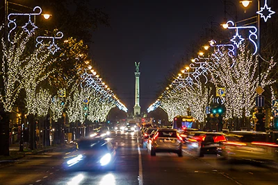 trees with festive lighting at night lining Andrassy ave, , the column at Heroes sqr. in the distance