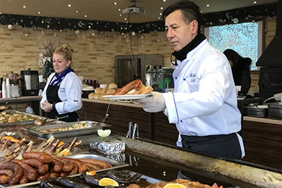 a man in white chef jacket handing a plate of food to a customer